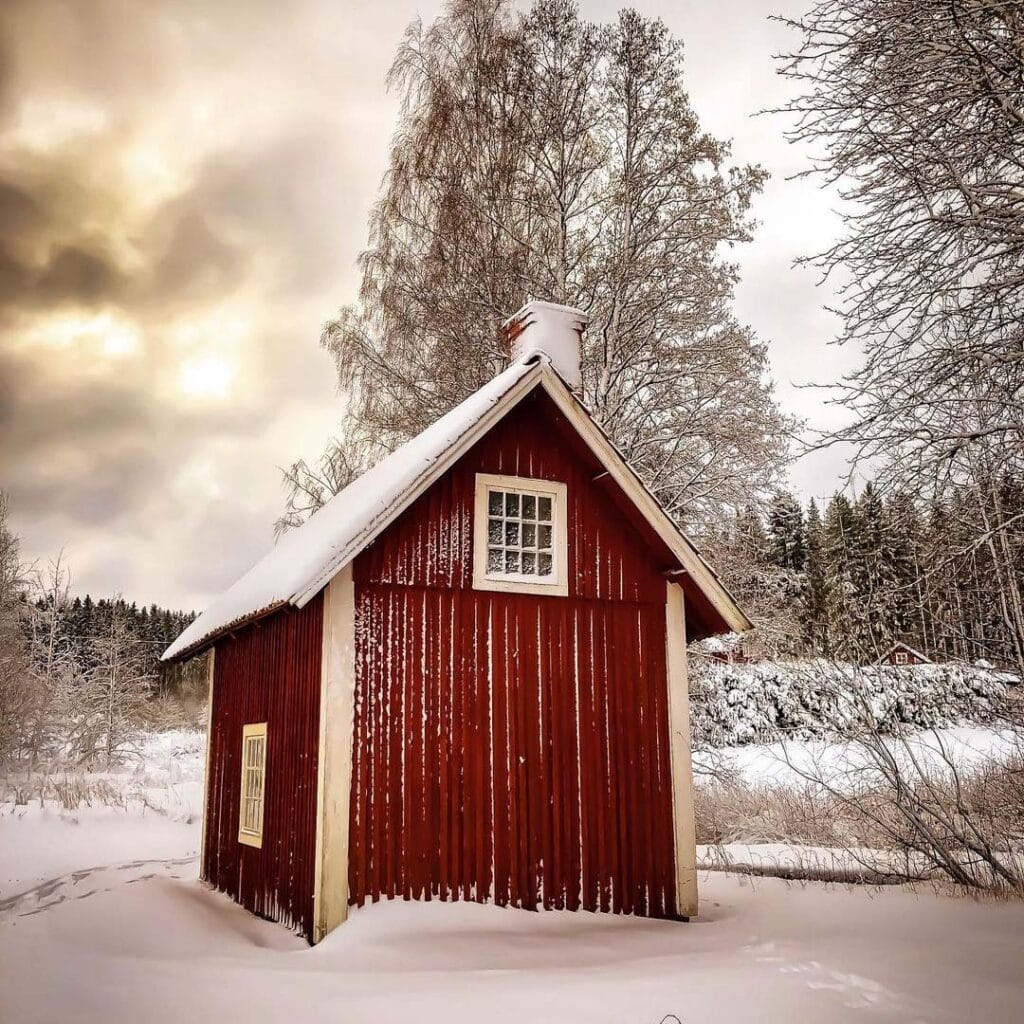 Röd liten stuga med vita knutar.